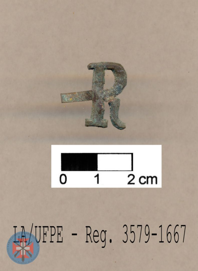 Peça na forma de letra 'R', em bronze, letra esta normalmente associada ao 'Regimento de Segurança' da polícia republicana, no início do século XX